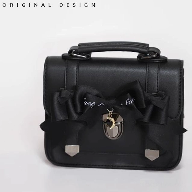 Black bow Jirai Kei Cambridge handbag with all-black bow featuring letter print and central metal lock pendant, structured flat lay photography