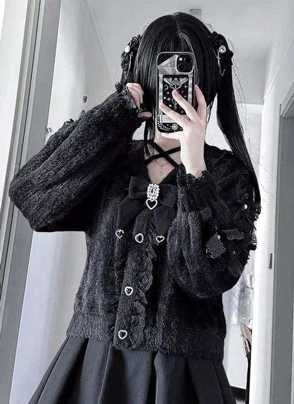 Half-length mirror selfie of black ruffled Jirai Kei cardigan with fuzzy puff sleeves, heart buttons, and cross ornament worn with twin-tails