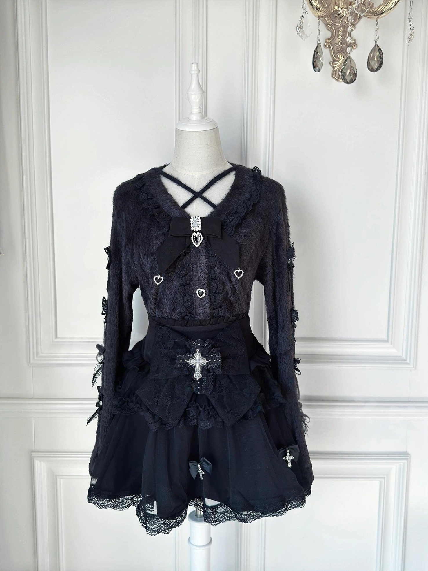 Black Jirai Kei cardigan and tulle skirt two-piece set with heart-shaped buttons and cross bow decoration displayed on dress mannequin front view gothic lolita style
