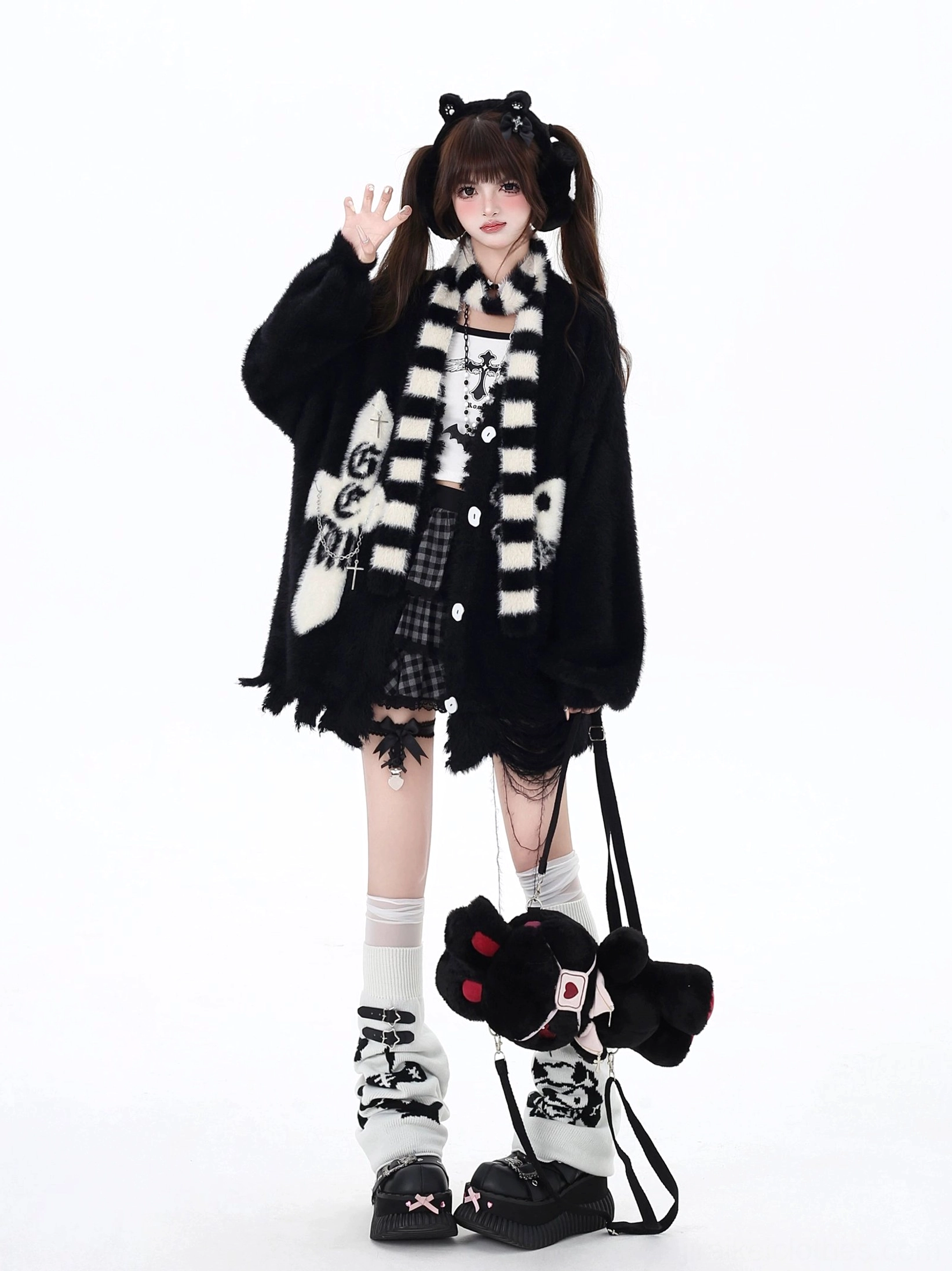 Black Jirai Kei irregular hem cardigan with cross and skull embroidery, paired with black-white striped scarf, worn by female model with twin-tail hairstyle in studio setting