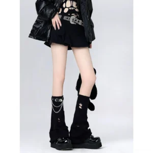 Black distressed Jirai Kei flared mid-calf leg warmers with metal chain buckle trim, front low-angle view on model wearing dark punk outfit