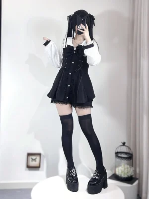 Black Jirai Kei two-piece dress set with rhinestone buttons and white puff sleeves worn by dark-haired model with twin tails in studio mirror view