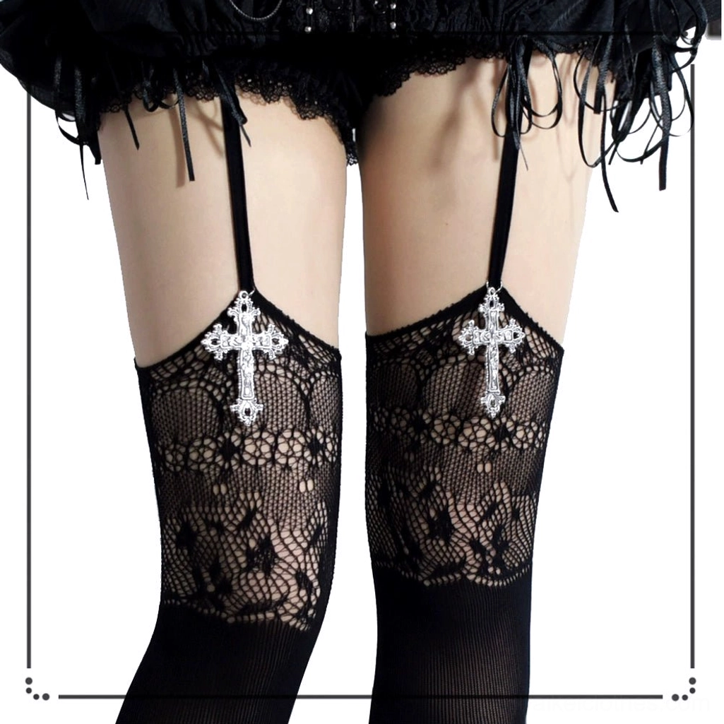 Close-up detail of black gothic jirai kei garter stockings showing intricate floral lace texture, silver cross pendant charm, and black garter strap construction