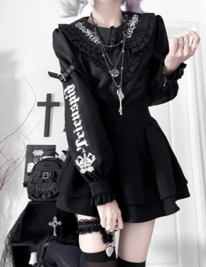 Black Jirai Kei gothic blouse with skull typography and ruffled peter pan collar paired with pleated mini skirt, front half-body styling shot
