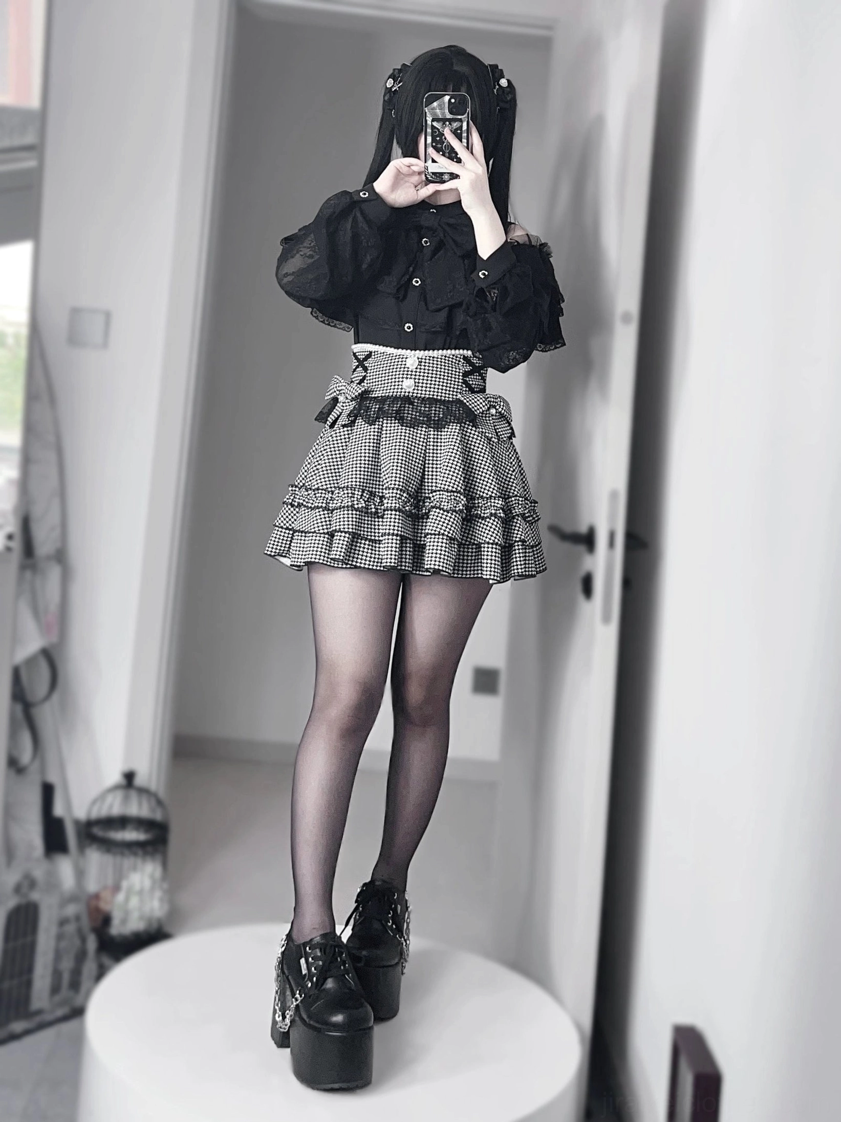 Black jirai kei ruffle mini skirt with houndstooth pattern and lace blouse front view, hooded gothic model wearing sheer black tights and boots