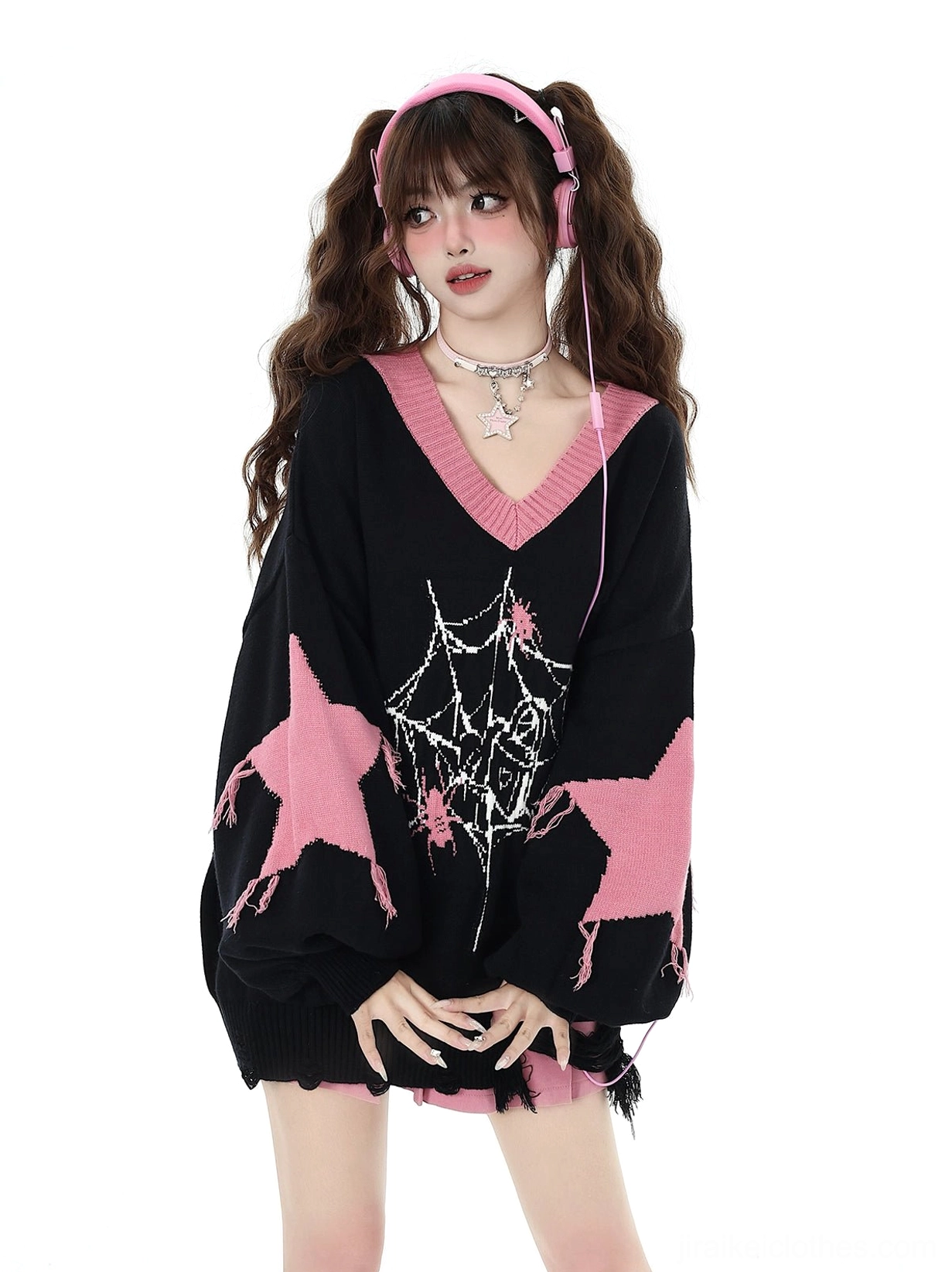 Black V-neck core-spun yarn knit sweater with pink star and spider web print worn by model with twin tails and pink headphones showing frayed hem detail