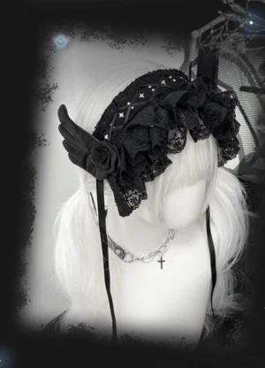 Black jirai kei lace hairband with winged ornaments and rivets worn on platinum twin ponytails left three-quarter view showing intricate wing decoration and fabric rose accents