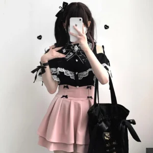 Black Jirai Kei lace off-shoulder blouse styled with pink pleated skirt on model in indoor studio selfie showing off-shoulder design