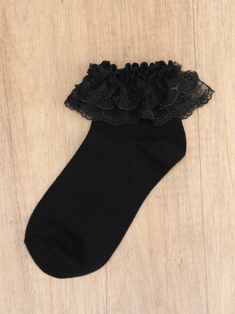 Single black Jirai Kei lace ruffle ankle sock flat lay side view on wood background multi-layered ruffled cuff texture detail