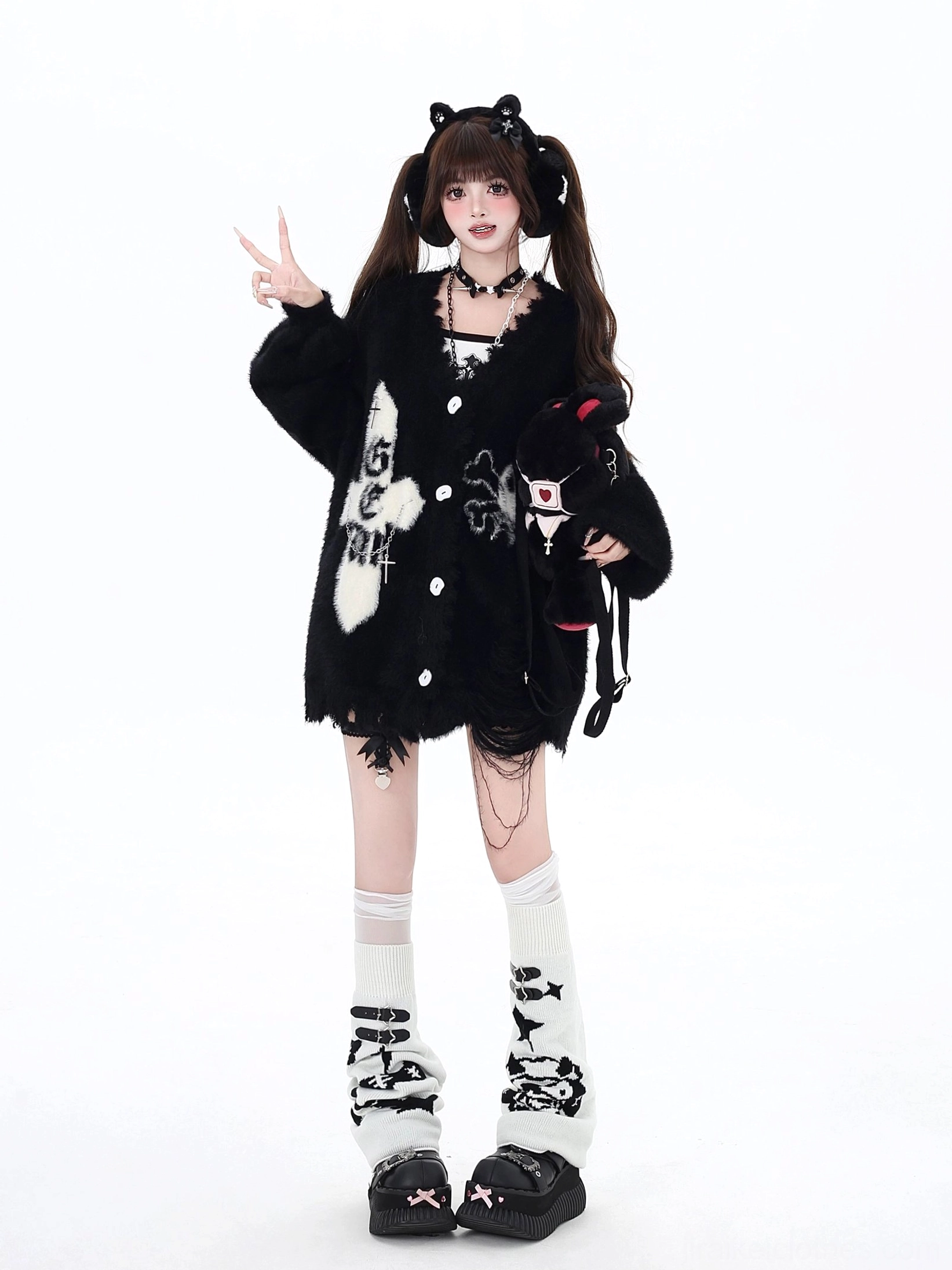 Black oversized Jirai Kei cardigan featuring cross and skull embroidery, relaxed button-up silhouette, worn with cat-ear headband and holding plush doll accessory