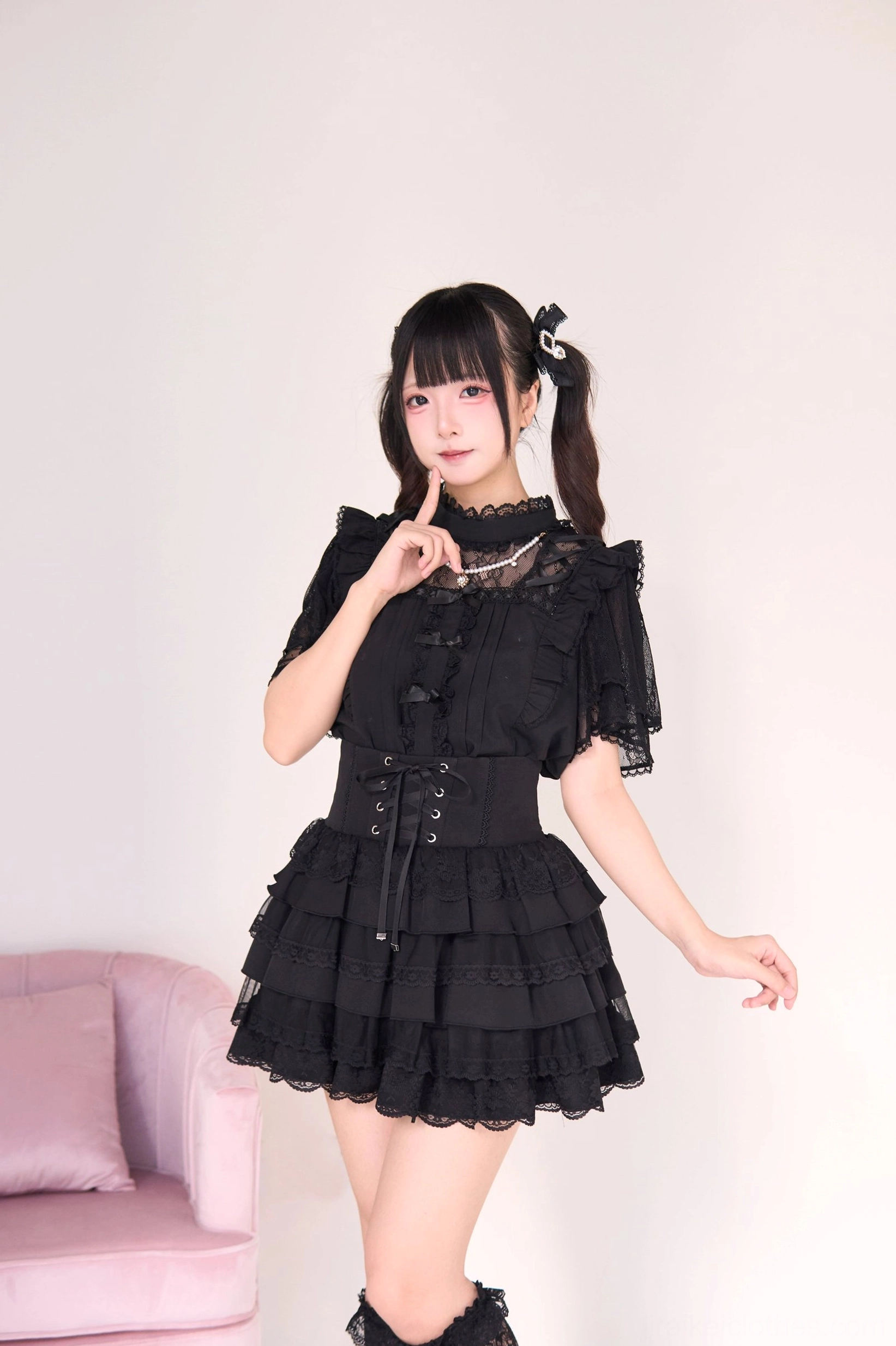 Black gothic lolita jirai kei blouse and tiered cake skirt featuring pearl necklace accessory, three-quarter front view showing corset waist dramatic layered ruffle skirt detail