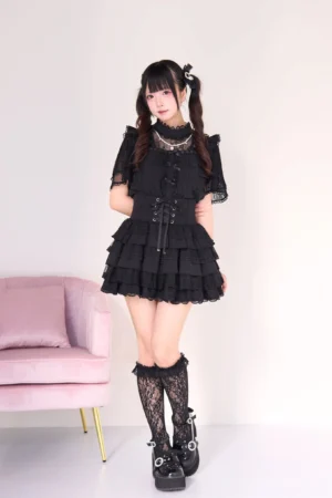 Black gothic lolita jirai kei blouse and tiered cake skirt set with pearl necklace accent, front full-body shot featuring lace sleeves corset waist and layered ruffle skirt with fishnet stockings