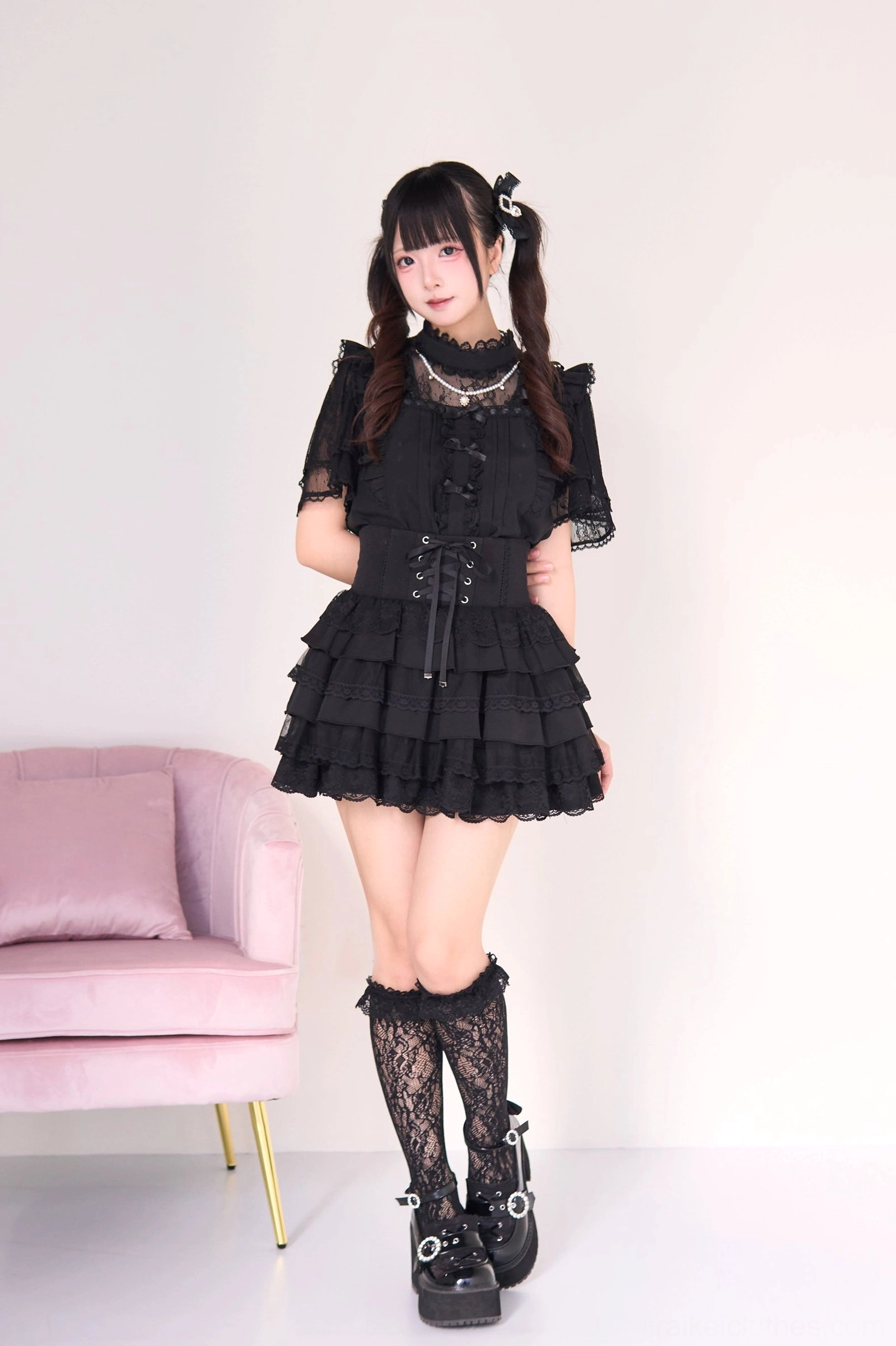 Black gothic lolita jirai kei blouse and tiered cake skirt set with pearl necklace accent, front full-body shot featuring lace sleeves corset waist and layered ruffle skirt with fishnet stockings