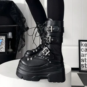 Close-up side three-quarter view of black platform combat boots with adjustable metal buckle straps, studded trim details, and thick platform heel on white display platform, showcasing Jirai Kei subculture boot design