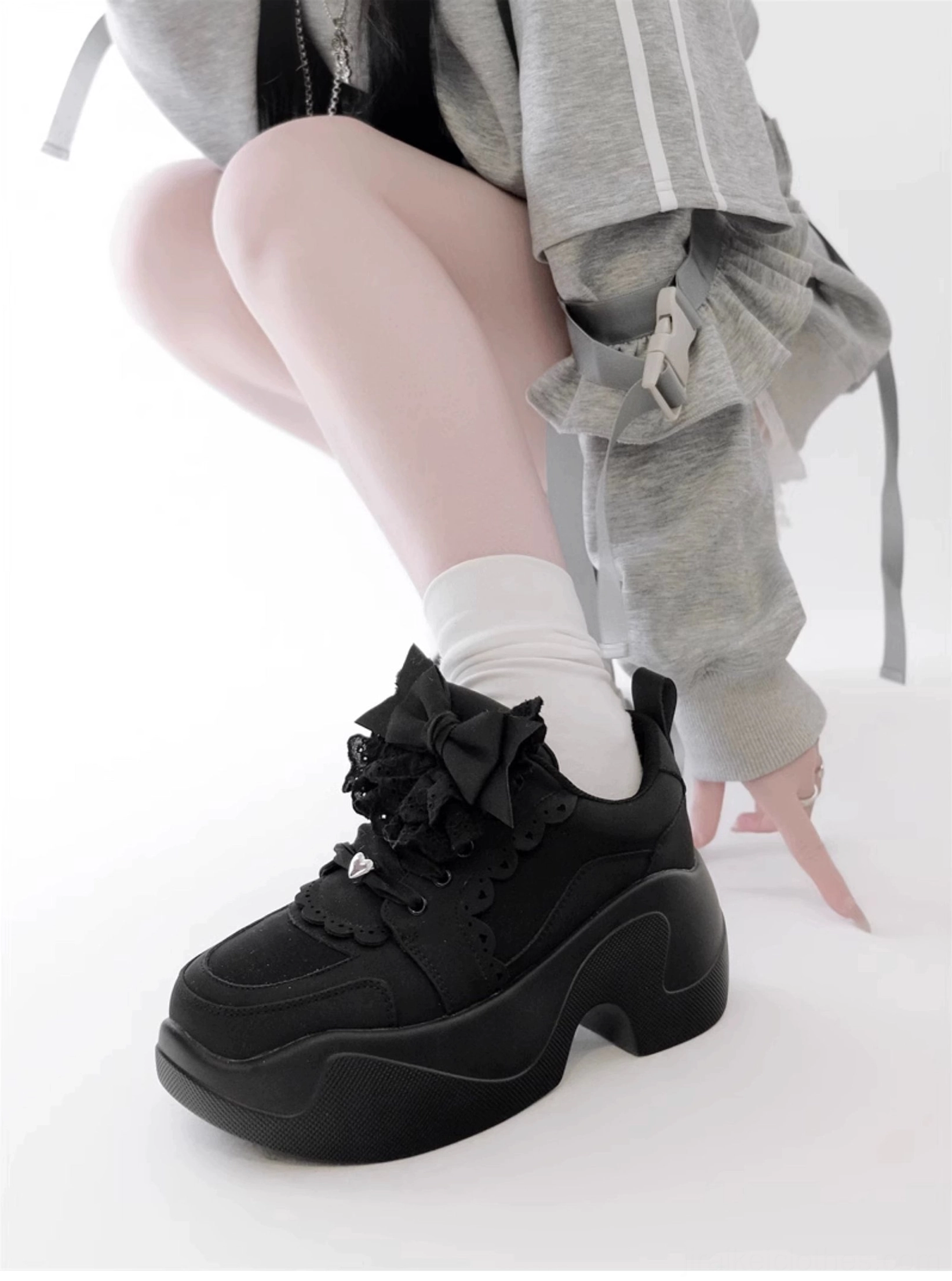 Black Jirai Kei platform sneakers low front single foot view model gray cropped jacket white crew socks lace bow decoration ruffled trim chunky sole
