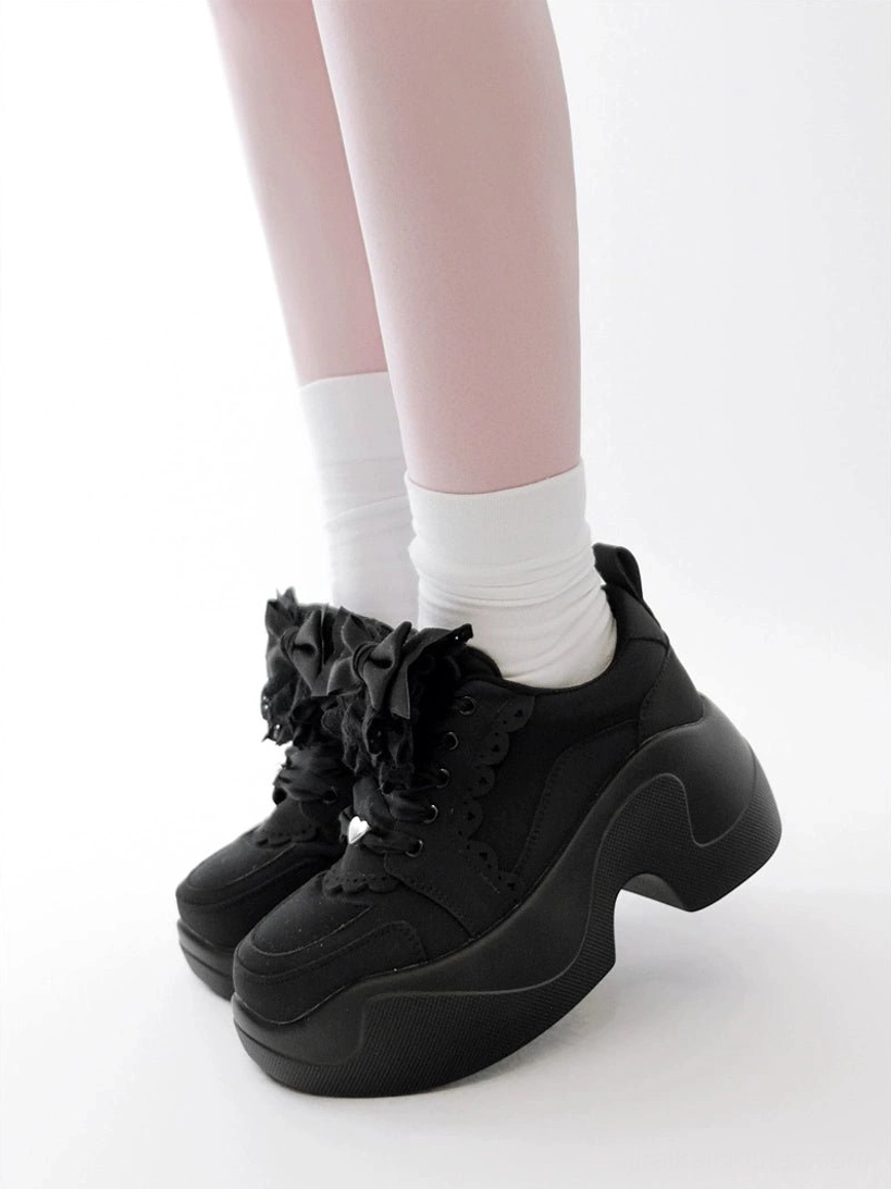 Black Jirai Kei platform sneakers paired shoe view low front angle chunky platform lace bow details matte black finish studio background