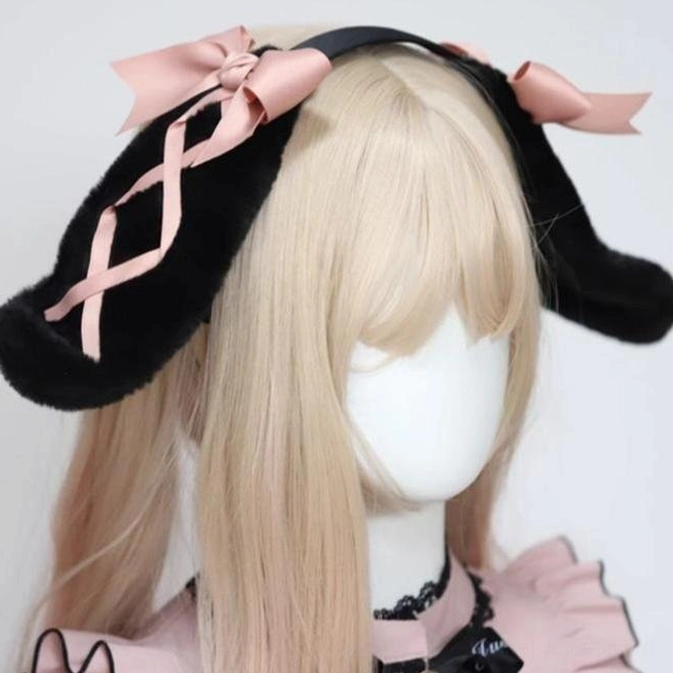 Black rabbit ear hairband worn on mannequin with pink lolita outfit three-quarter view showing fluffy black ears and pink ribbon details