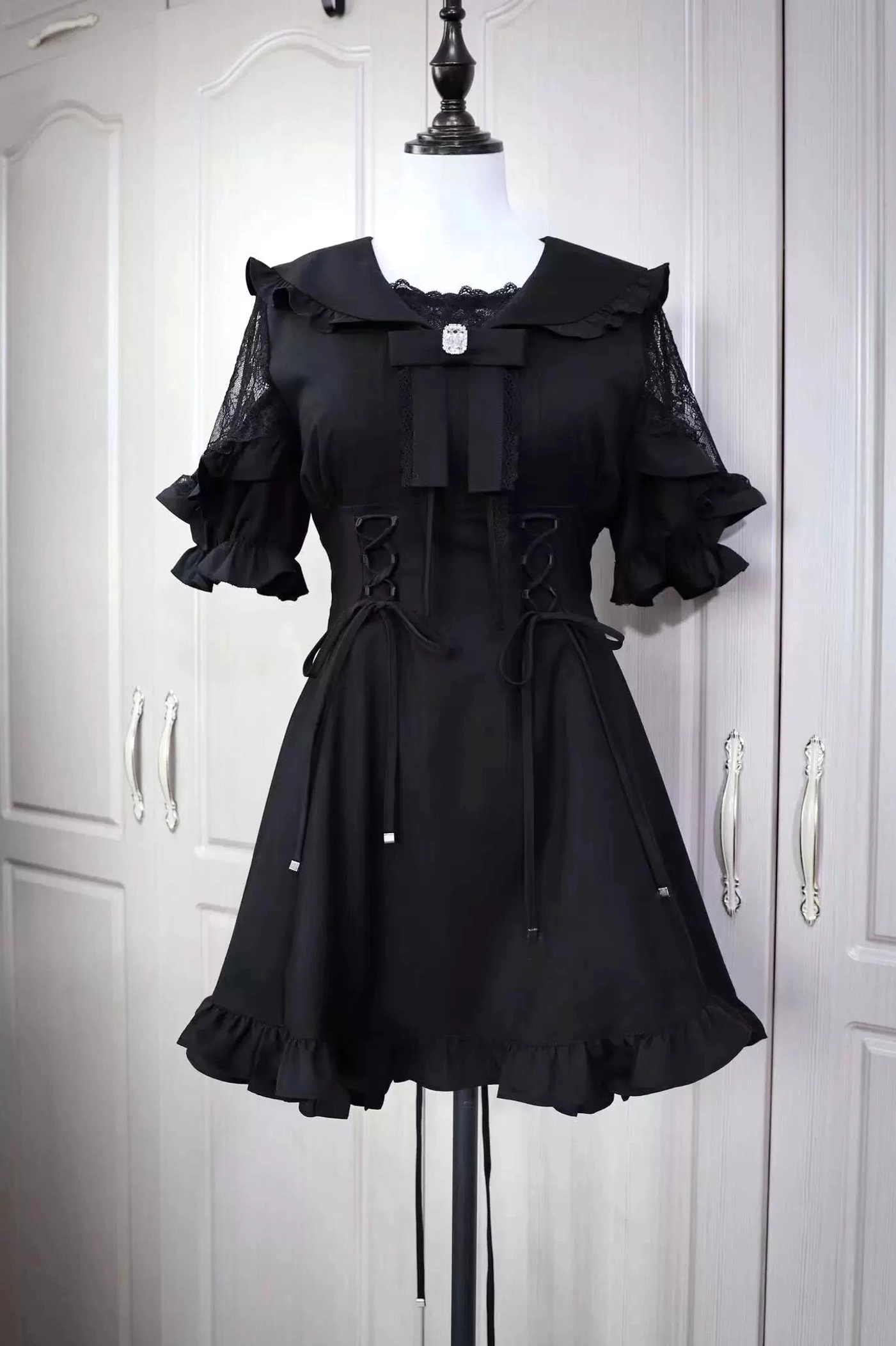 Black Jirai Kei sailor dress with lace ruffle sleeves and corset lacing displayed on dress form front view
