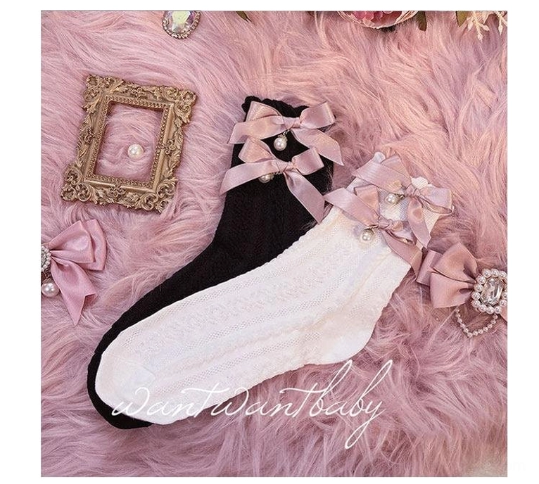 Flat lay top-down view of black and white lolita short socks with satin pink bow, pearl and rhinestone embellishment, cable knit texture detail, pink faux fur backdrop