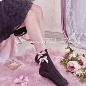 Black lolita short socks with pink bow and pearl pendant worn with dark tulle skirt, model shot showing ankle styling, Jirai Kei fashion aesthetic