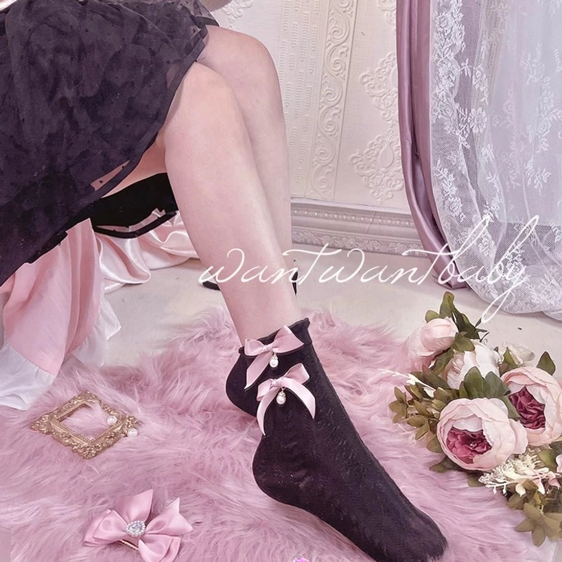 Black lolita short socks with pink bow and pearl pendant worn with dark tulle skirt, model shot showing ankle styling, Jirai Kei fashion aesthetic