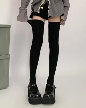 Black over-the-knee socks direct front leg shot on model with rolled sock tops and platform leather shoes gray oversized top