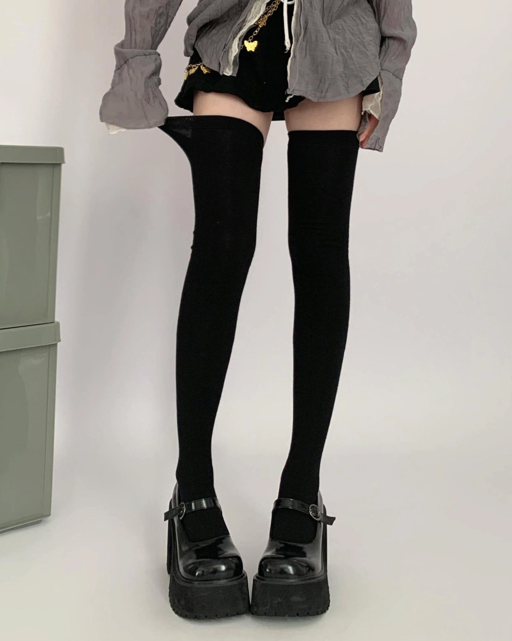 Black over-the-knee socks direct front leg shot on model with rolled sock tops and platform leather shoes gray oversized top