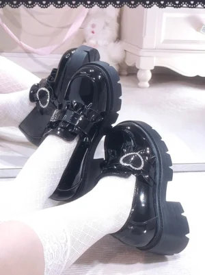 Black patent leather Jirai Kei platform loafers with heart rhinestone buckle detailed close-up side view showing glossy PU material and thick lug sole in romantic bedroom aesthetic