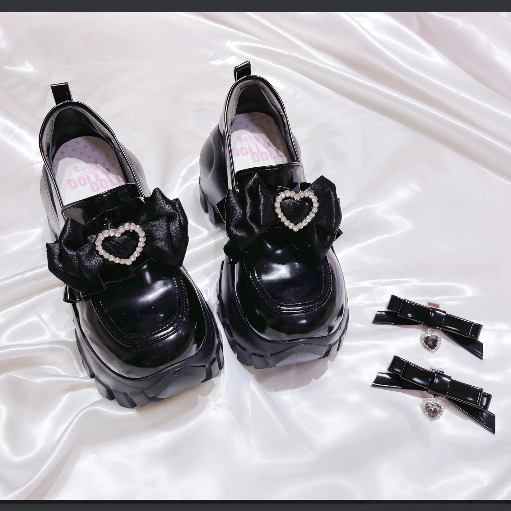 Black patent JK platform shoes showcasing glossy finish, heart rhinestone bow decoration, thick chunky sole, studio close-up