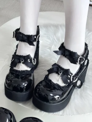 Black patent leather Jirai Kei platform shoes with cross pendant and heart rhinestone buckle, front overhead view featuring glossy finish, thick block heel, decorative ankle straps, satin bows, and lace trim detailing