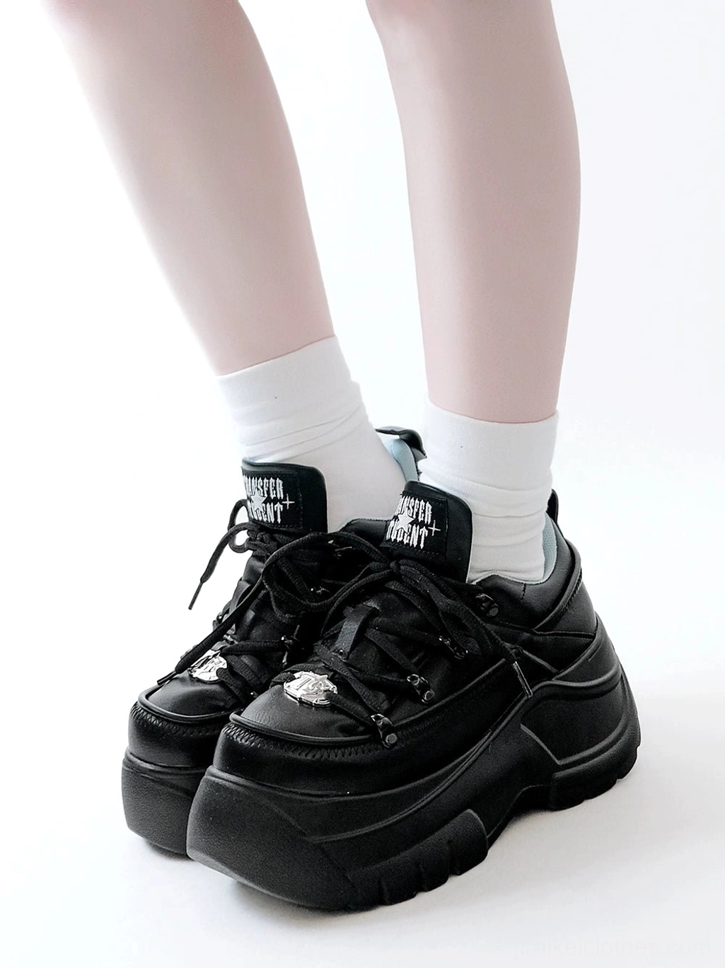 Black platform jirai kei sneakers low angle side view of both feet with white crew socks showcasing chunky foam outsole and metal toe decoration