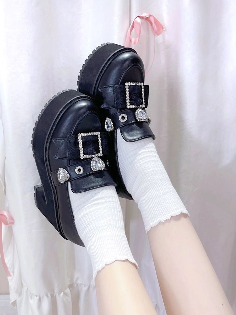 Top-down close-up of black patent leather Jirai Kei platform loafers showing chunky sole and rhinestone buckle embellishments with charms
