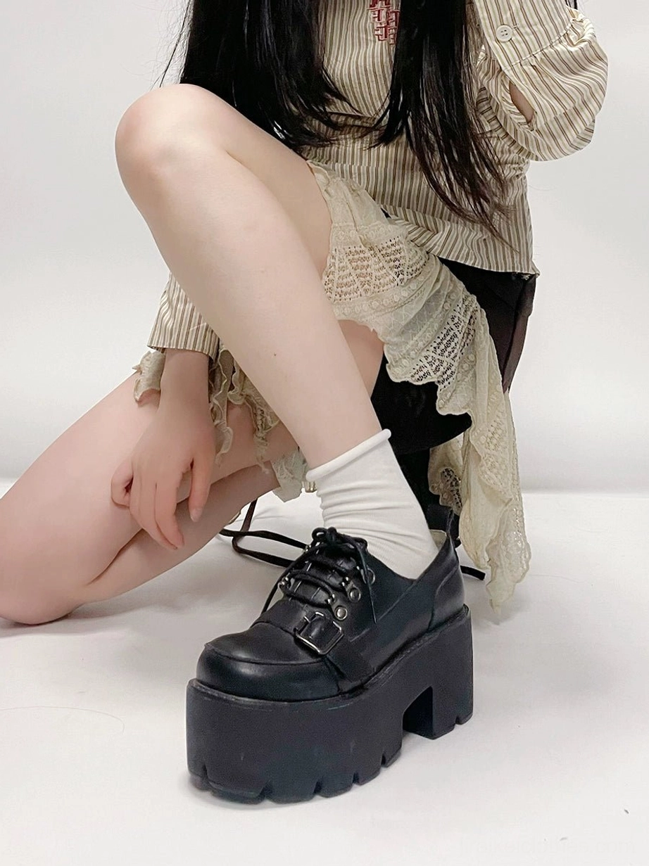Single black platform derby shoe low angle side view on seated model showing thick lug platform sole and lace closure detail