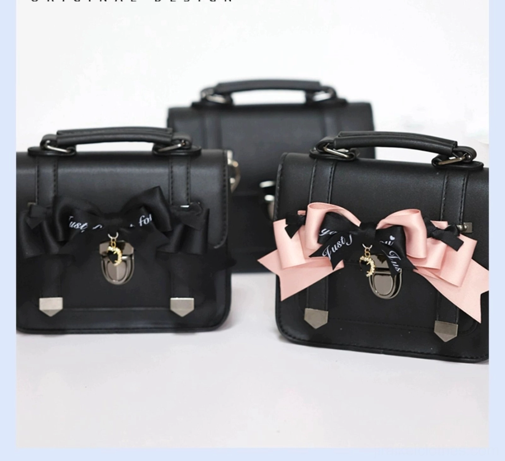 Premium black PU leather Jirai Kei Cambridge bag with bow decoration and metal lock hardware, angled product photography with blue border frame
