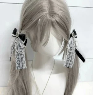 Black Ryousangata lace bow hair clips with dangling crystal tassel worn on gray twin-tail mannequin wig, side view showcasing Jirai Kei styling