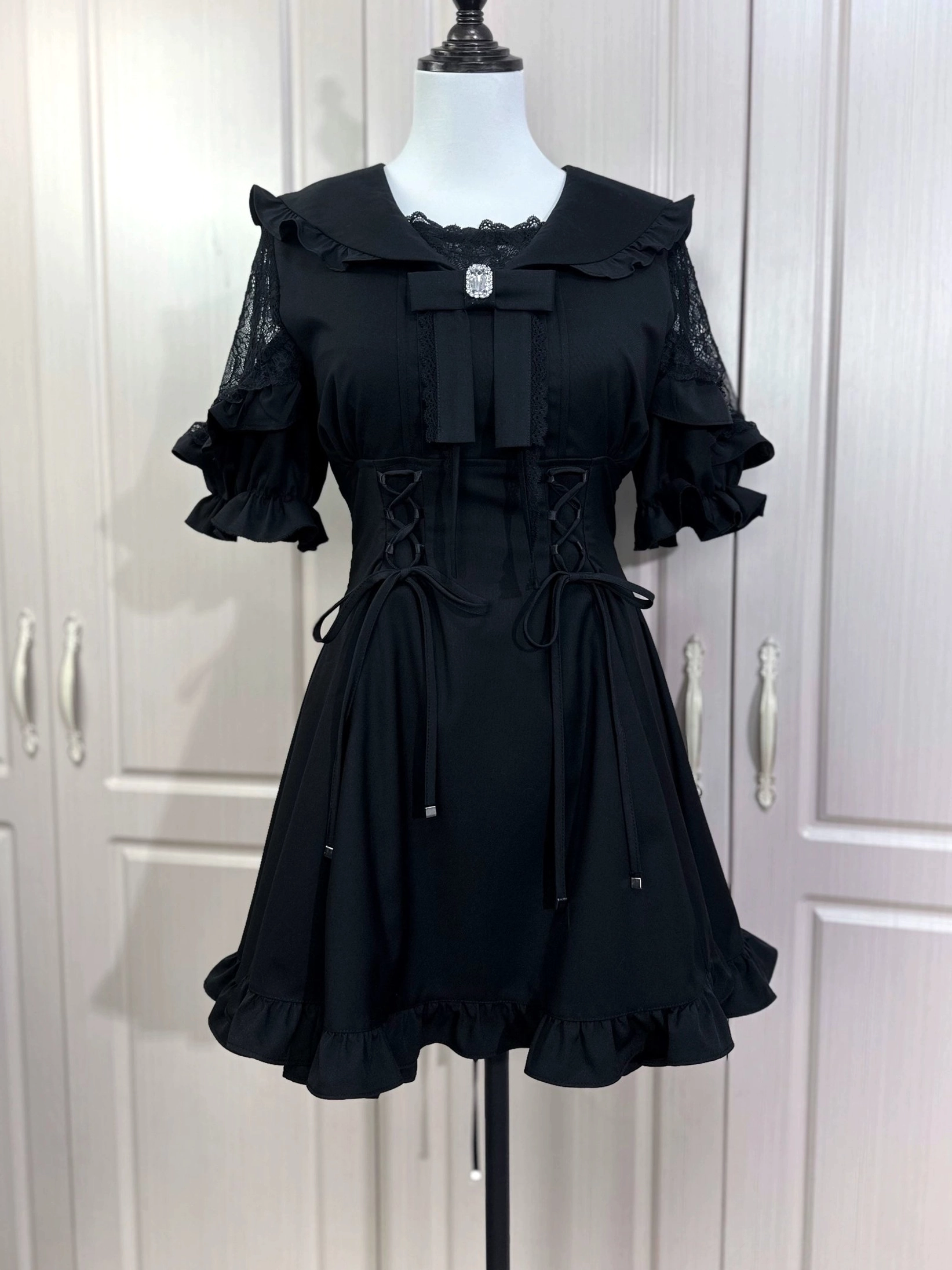 Black slim fit sailor Jirai Kei dress with flared ruffled sleeves and large collar bow detail on mannequin
