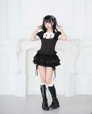 Black striped Jirai Kei blouse with white Peter Pan collar and tiered skort set, styled with black combat boots and lace white socks, front view studio portrait
