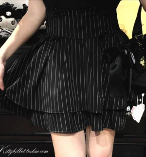 Black vertical striped Jirai Kei skirt with double-layer ruffled hem, visible built-in shorts, and black bow decorations, side-back half-body styling shot