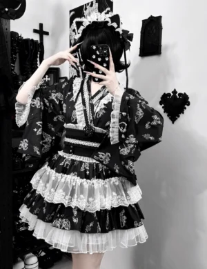 Black-white gothic yukata wing-print two-piece set worn by model with wide kimono sleeves and tiered ruffle skirt, front selfie angle showcasing dark aesthetic