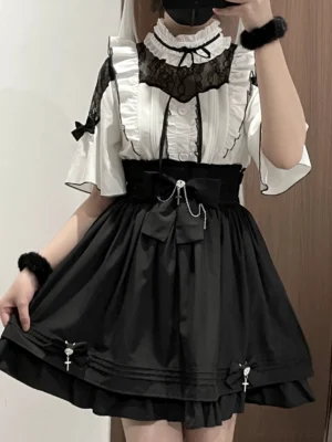 Half-body mirror selfie of black and white jirai kei outfit set with lace collar blouse, high-waist black skirt, bow details and cross pendant accents worn by female model