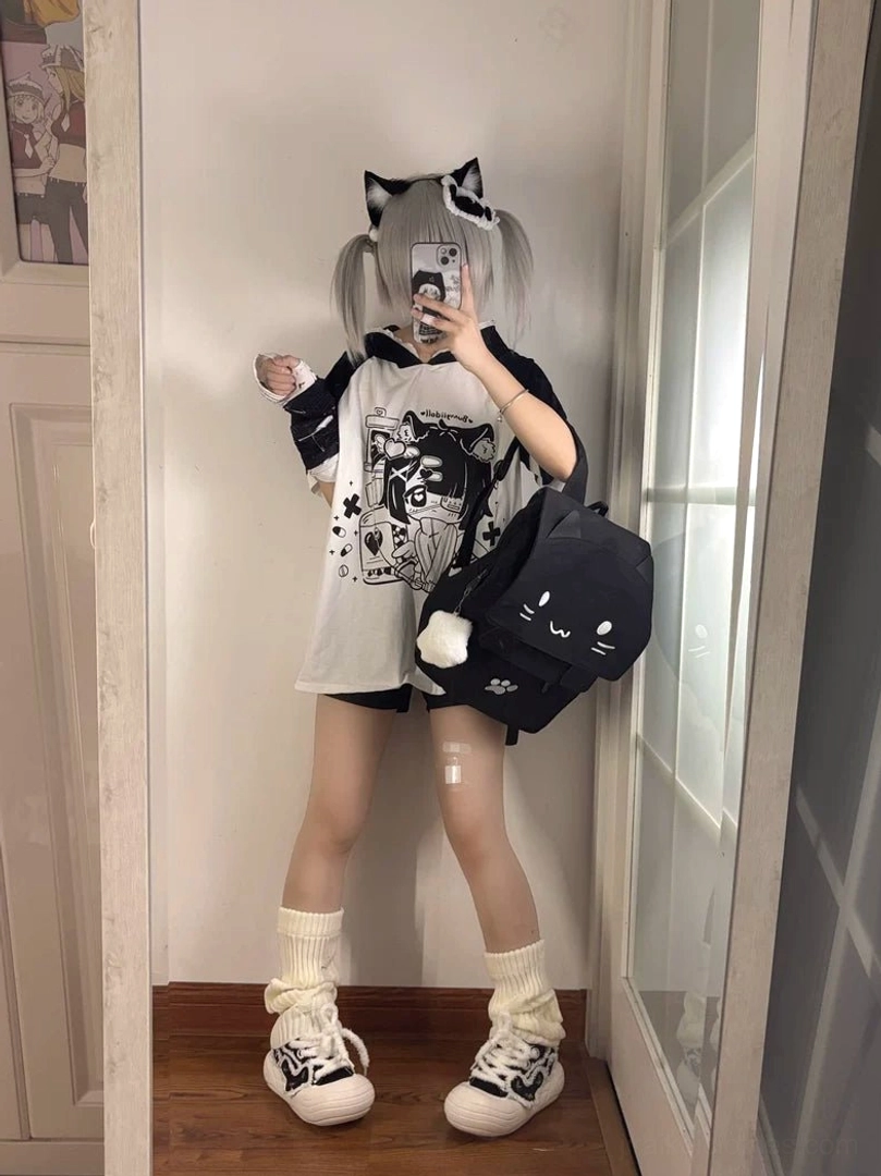 Full-length mirror selfie of model wearing black and white yami kawaii cat ear hooded anime graphic tee with loose fit, cat ear backpack, and frilly cotton socks