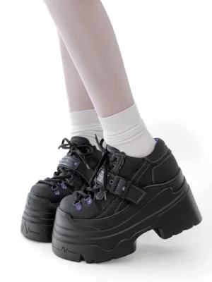 Black Y2K jirai kei chunky platform shoes with purple eyelet accents and strap detail, worn with white socks on female model, side view lower leg