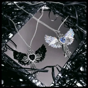Blue Y2K Jirai Kei winged cross necklace with silver filigree cross pendant and blue rhinestone heart centerpiece on white background