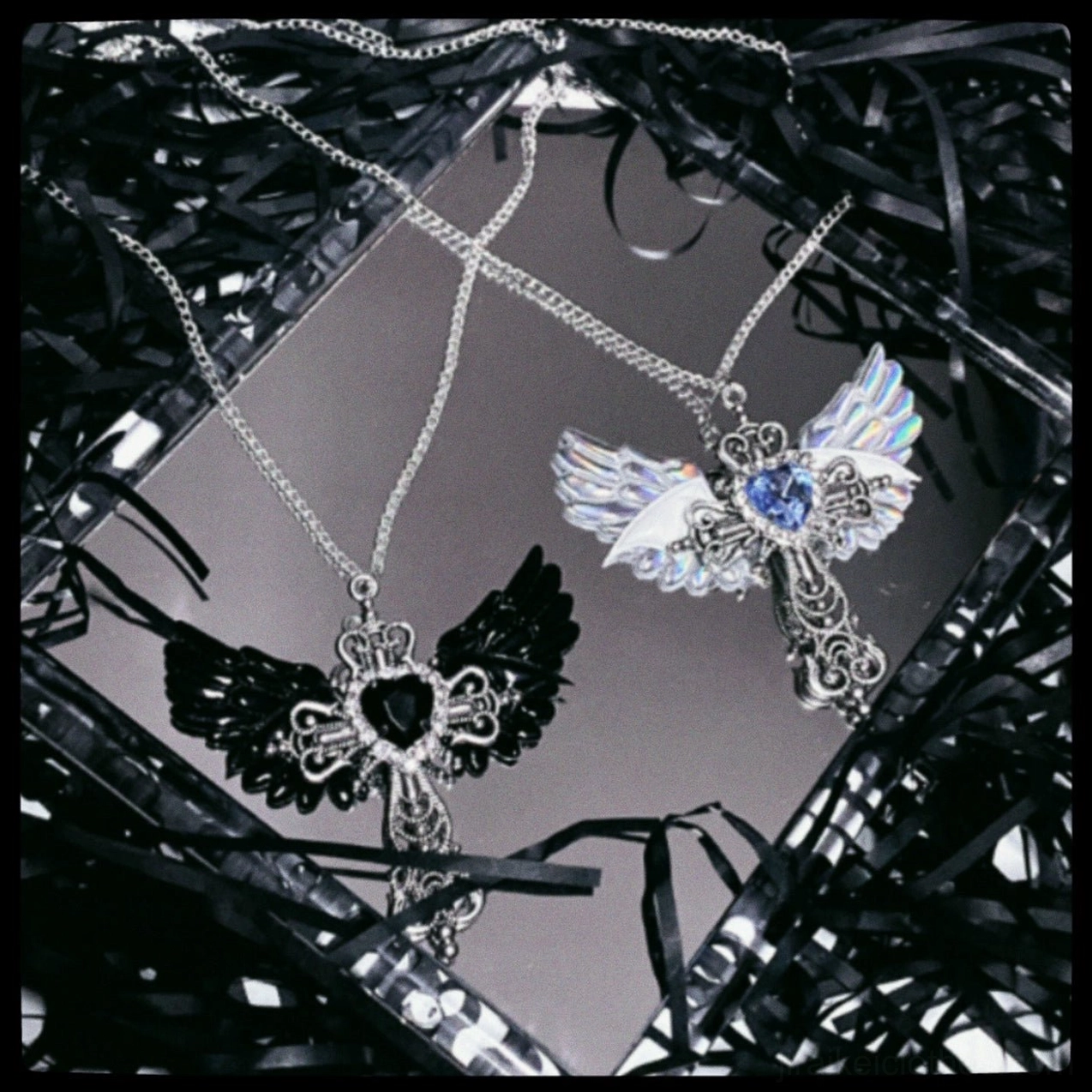 Blue Y2K Jirai Kei winged cross necklace with silver filigree cross pendant and blue rhinestone heart centerpiece on white background
