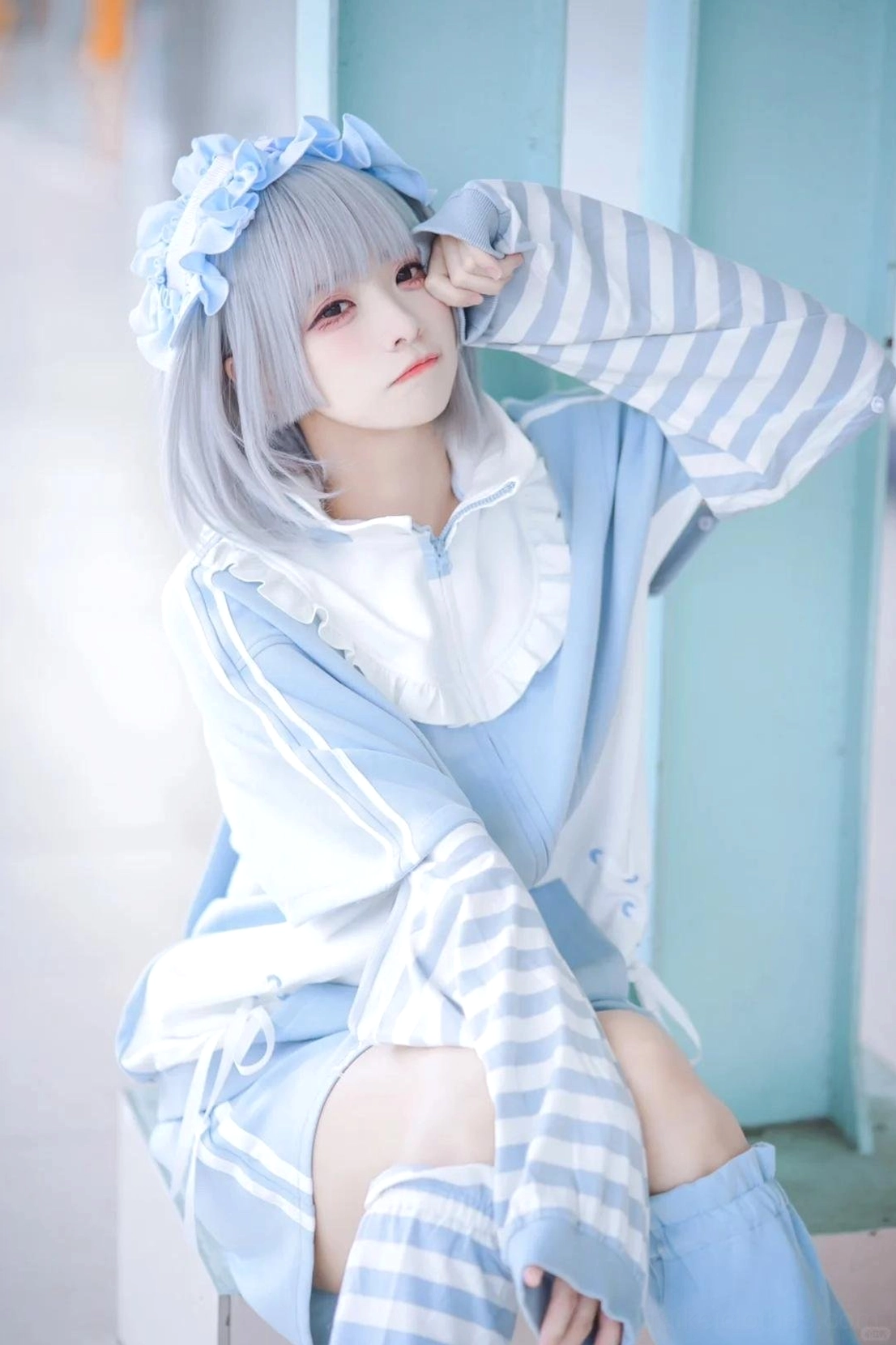 Side profile view of blue Tenshi Kaiwai sweet lolita hoodie outfit with peter pan ruffled collar, striped leg sleeves, and blue floral hairband on silver grey hair model