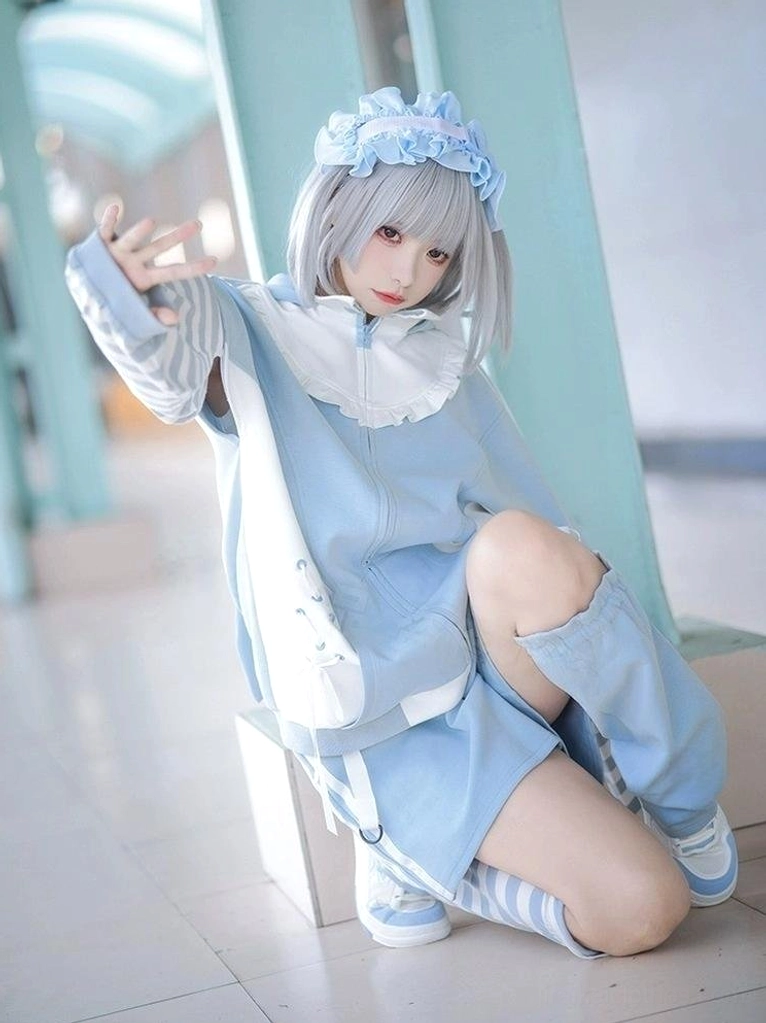 Three-quarter angle view of blue Tenshi Kaiwai lolita hoodie set featuring cutout shoulder design, matching blue hairband, and loose shorts on cosplayer model
