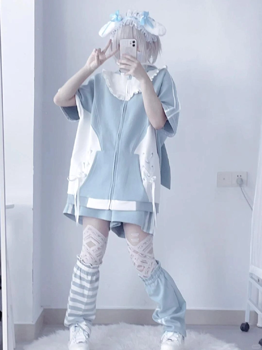 Mirror full-body view of blue oversized Tenshi Kaiwai hoodie dress set with ruffled collar, striped leg sleeves, and bow blue headwear on silver grey hair model