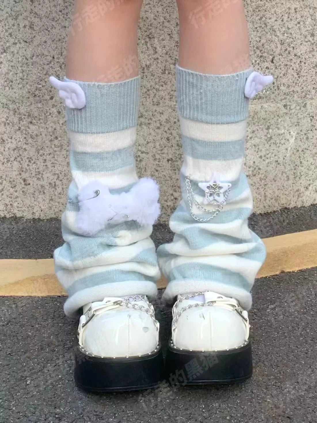 Low-angle outdoor front view of light blue and white striped leg warmers with angel wings fluffy bow and star chain charms with silver-accented platform shoes