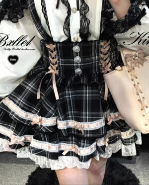 Black plaid Jirai Kei suspender skirt with pink ribbon lace-up details and layered ruffled hemline front view detail shot