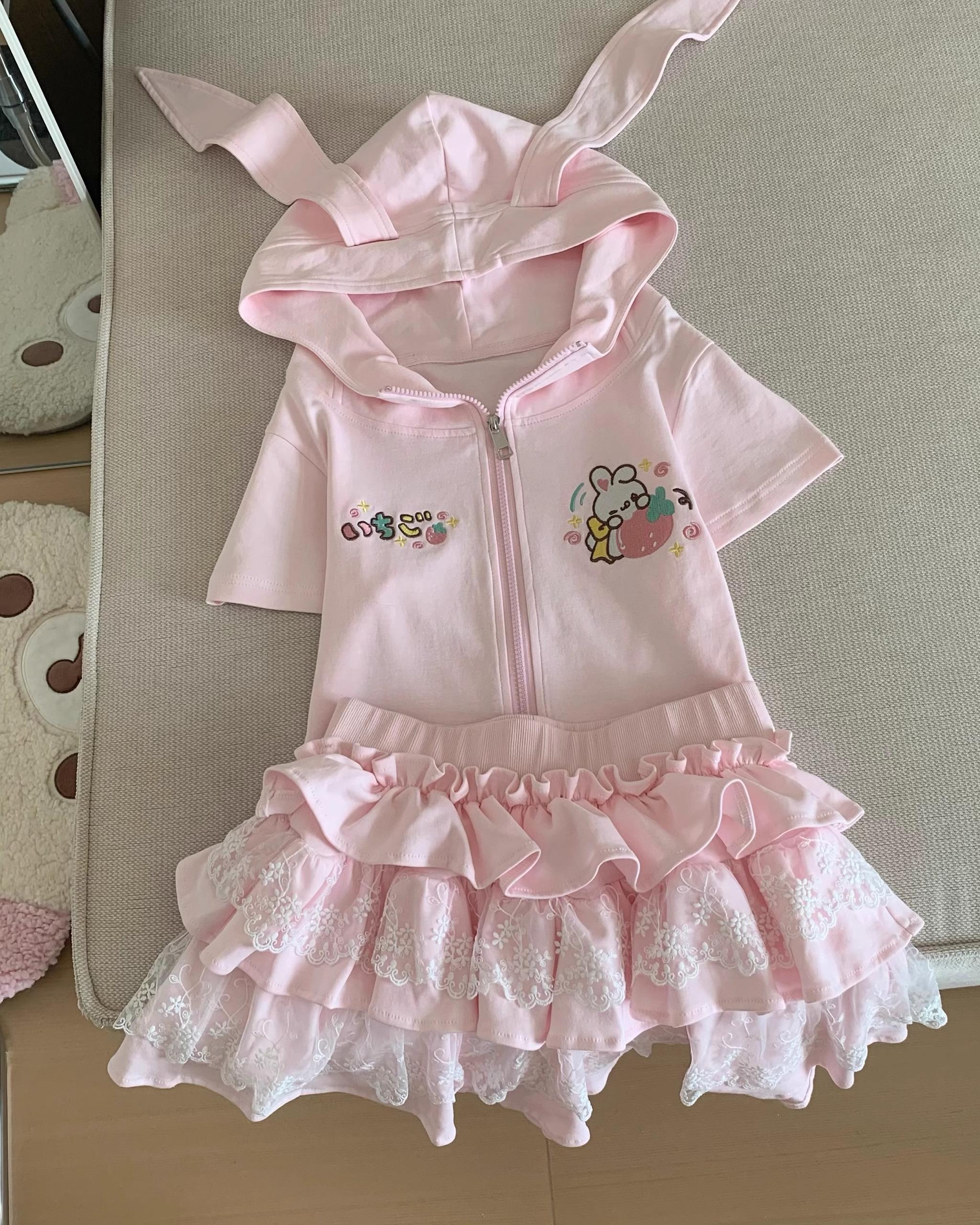 Pastel pink zip-up short-sleeve hooded top with bunny ears and three-tier lace ruffle cake skirt on dress form front display